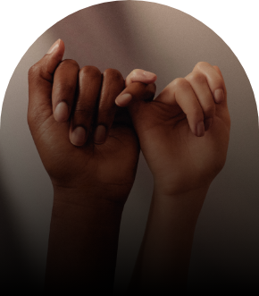 Two hands linked together by the pinkie finger on each. One hand is Black and one hand is white.